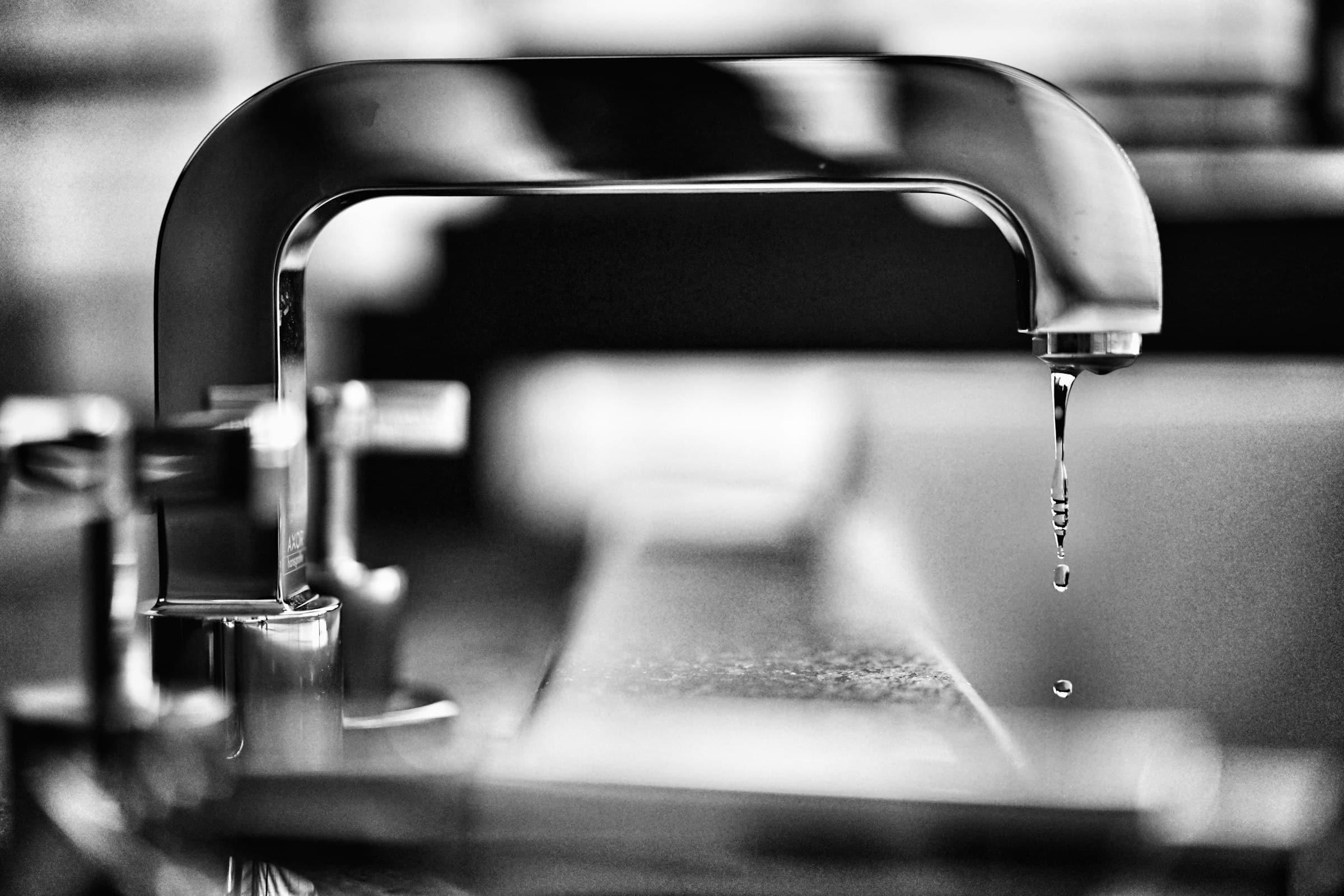 Close-up of a faucet with a single drop of water forming at the spout
