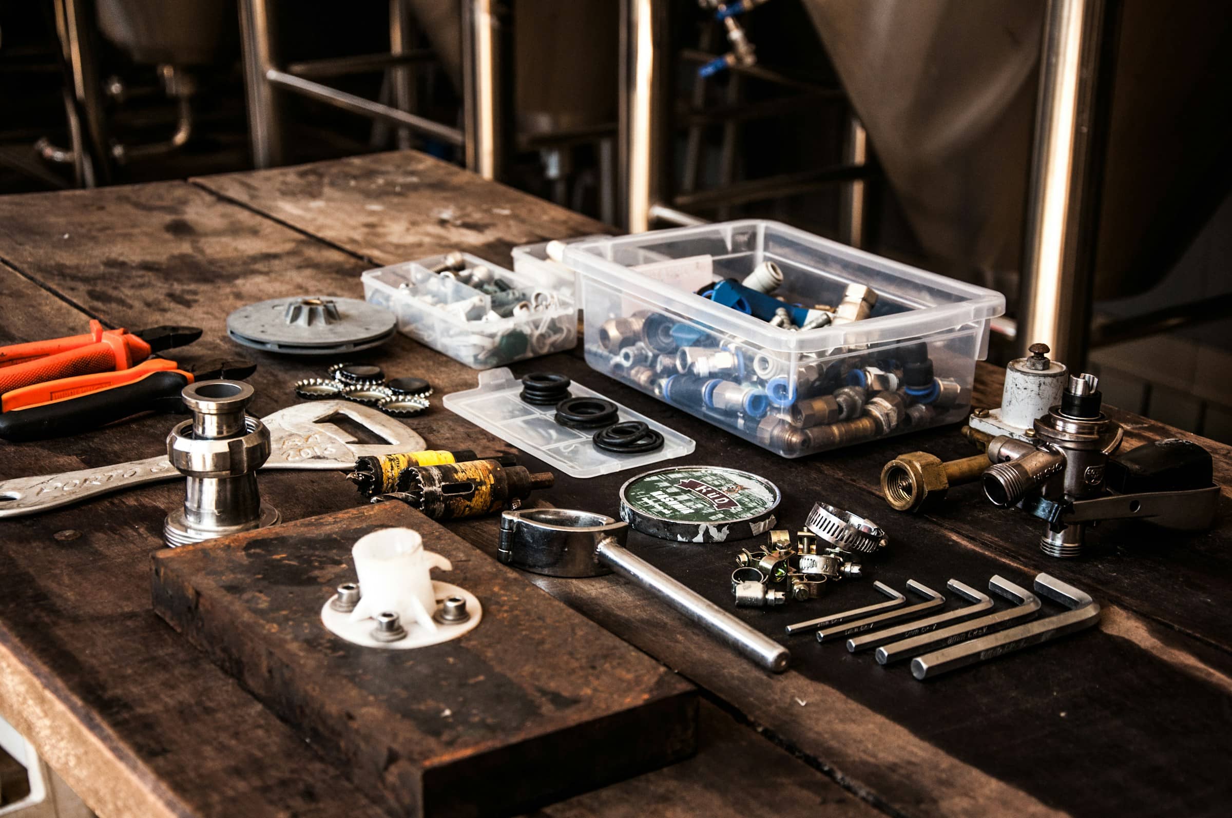 Plumbing fittings, clamps and hand tools laid out on a workbench