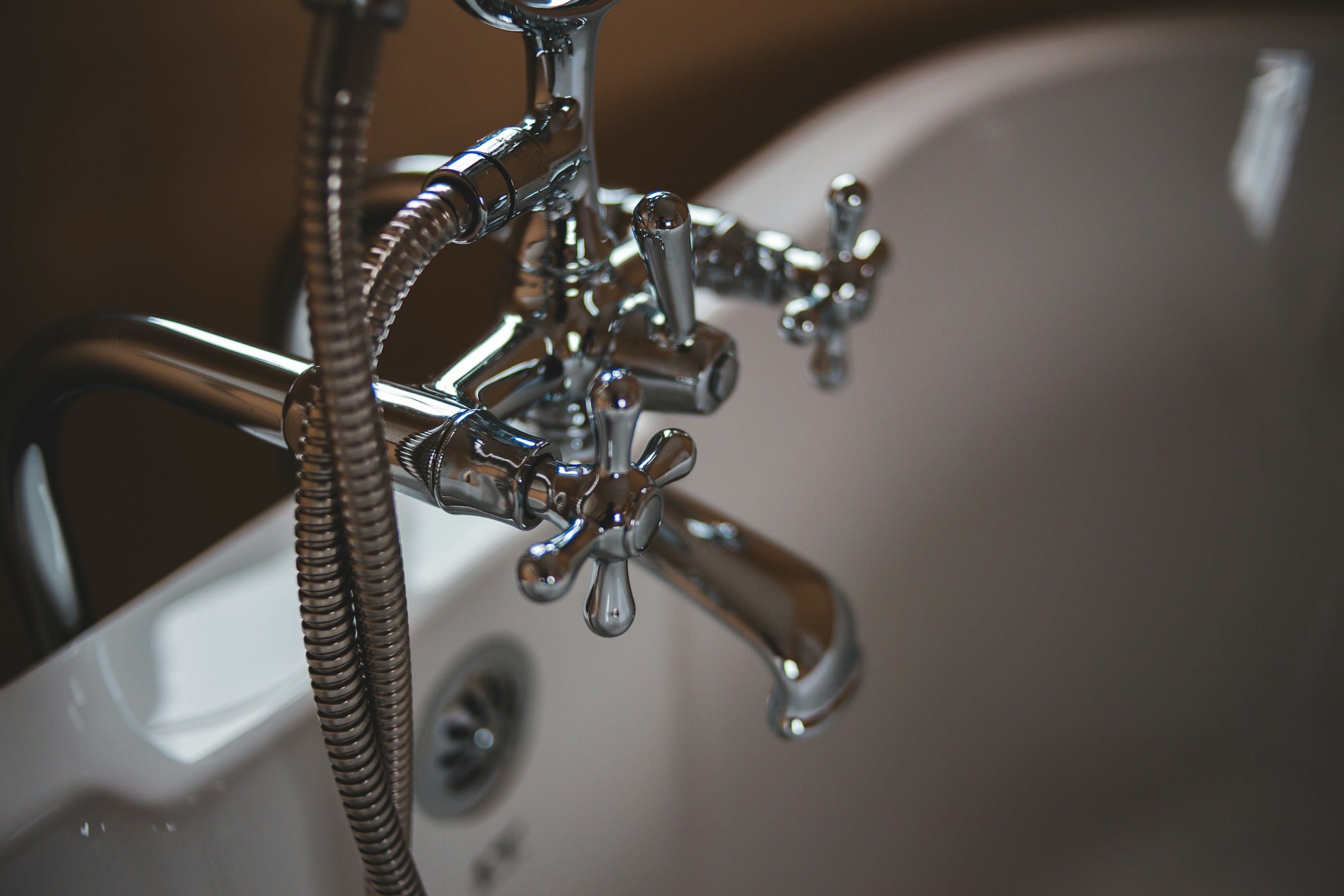 Chrome tub filler and cross-handle valves on a white bathtub